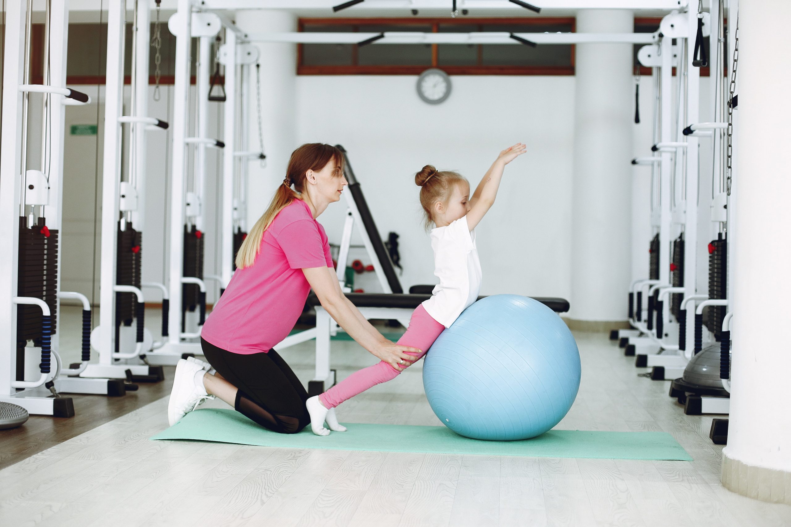 Mother with little daughter are engaged in gymnastics in the gym